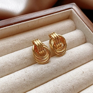 Close-up of golden vintage knot earrings placed in a premium linen jewelry display box