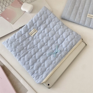 Close-up of blue gingham quilted tablet sleeve with ribbon bow and zipper detail
