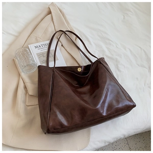 Macro shot of dark brown soft leather tote bag with magnetic metal clasp and large capacity