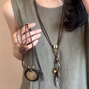 Collier bohème vintage avec disque en métal, plumes et perles sur cordon marron