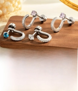 Detailed macro view of U-shaped titanium steel earrings with inlaid pink and blue zircons