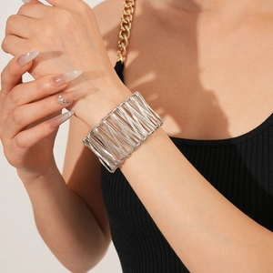Gros plan d'un bracelet manchette évidé en fil d'argent porté sur le poignet d'un mannequin