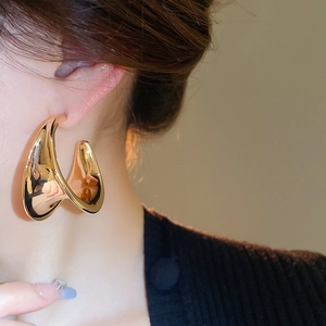 Close-up of a gold-toned liquid metal texture C-shape earring on a female model