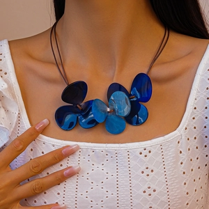 Detail shot of the large blue acrylic clover pendant on a brown double wax cord necklace
