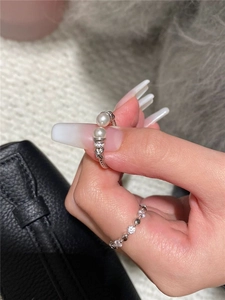 Close-up of minimalist silver rings with white pearls and sparkling cubic zirconia details