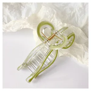 Detail of transparent green jelly bow hair claw clip with golden metal spring mechanism