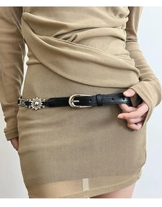 Close-up of black leather belt with silver sunburst floral metal buckle on knit dress