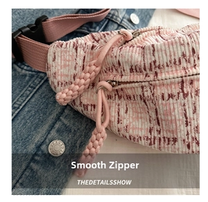 Detail of pink plaid corduroy chest bag with dual zippers and woven rope pullers