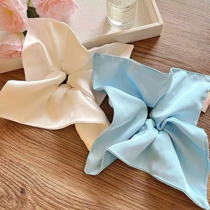 Elegant white and light blue silk satin hair scrunchies on a natural wood surface