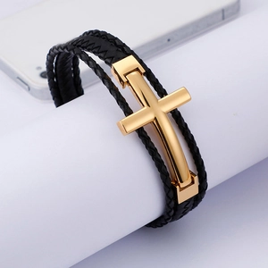 Macro shot of multi-layer black braided leather bracelet with golden stainless cross