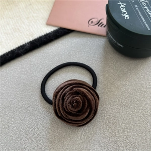 Detail of a brown velvet rose flower hair scrunchie with an elastic black band