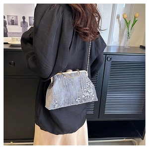 Grey sequined evening clutch bag with metal clasp and gold chain strap on model shoulder