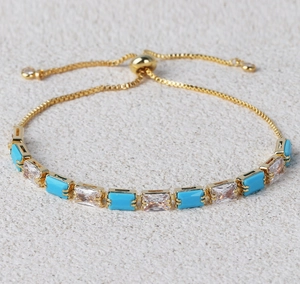 Detailed close-up of gold adjustable chain bracelet with turquoise and zircon stones