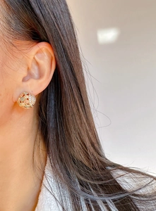 Detail of rose gold cutout flower earring with micro-set zircons on a model's ear