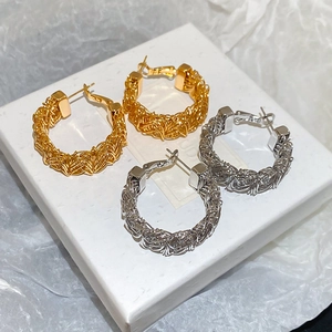 Macro detail of gold and silver braided hoop earrings with metal wire woven texture