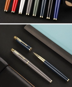 Detail of colorful metal rollerball pens with golden clips and blue notebook for business