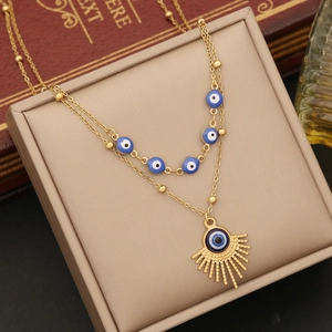 Detail of gold double-layer necklace featuring blue evil eye beads and sunburst pendant