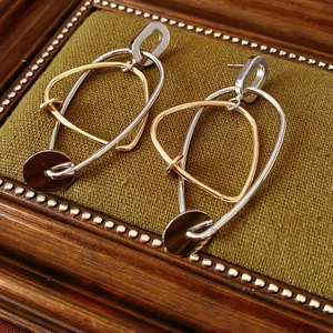 Vue détaillée de boucles d'oreilles géométriques bicolores sur velours vert et bois
