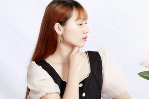 Detail of vintage oval gold-rimmed earrings with amber resin worn by a female model