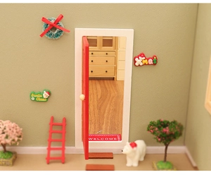 Detailed dollhouse scene with a red miniature door, festive wreath, and welcome mat accessories