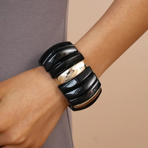 Close-up of a wide chunky acrylic bracelet featuring black and mirror gold segments