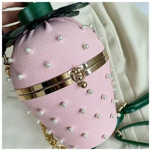 Détail du sac seau en forme de fraise rose avec perles blanches et feuilles en cuir vert