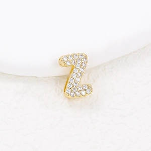 Detailed macro view of a gold-plated Z-shaped pendant encrusted with sparkling white zircons
