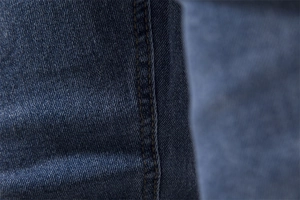 Macro shot of durable dark blue denim fabric with reinforced yellow double stitching