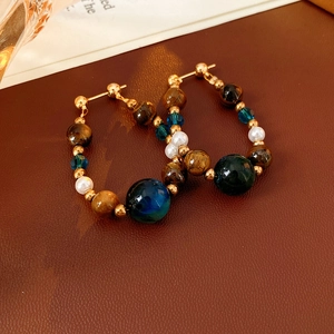 Detailed close-up of vintage drop earrings with tiger eye stone and pearls on leather