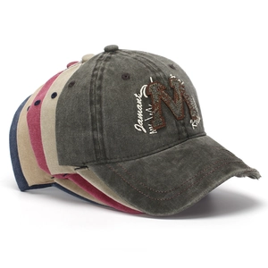 Close-up of stacked washed cotton baseball caps with M embroidery and worn brim details