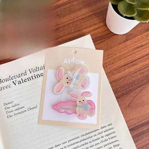 Detailed view of pink acrylic rabbit hair clips with Good Luck text on display card