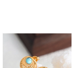 Detailed close-up of gold geometric earrings with turquoise stone and butterfly back