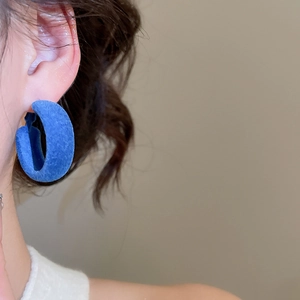 Gros plan de boucles d'oreilles créoles bleues floquées sur modèle avec texture velours