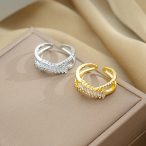 Detail of silver and gold criss-cross rings with sparkling zircon on soft fabric