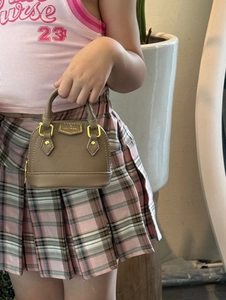 Nahaufnahme der beigen Mini-Muscheltasche aus Leder mit goldener Hardware und Logo