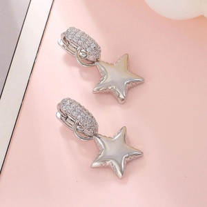 Detail view of silver heart and star earrings with pavé set cubic zirconia on pink background