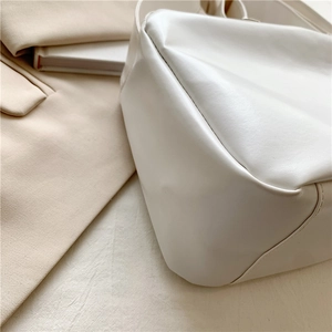 Minimalist white leather tote bag featuring a smooth texture and rounded stitching details