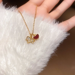 Détail du collier doré avec pendentifs chien en zircon et cœur rouge portés par un modèle