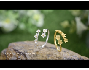 Detailed close-up of silver and gold forget-me-not flower rings on a natural stone