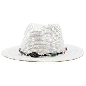 Close-up of white straw sun hat with beaded black rope band and vintage metal emblem