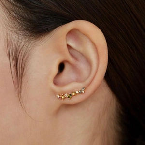 Macro view of a gold ear climber earring featuring multi-colored crystals and zircons