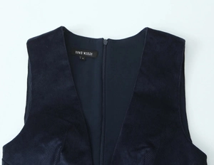 Detail of dark blue corduroy vest showing the V-neckline with zipper and inner label