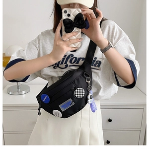 Detailed view of black nylon chest bag with fashion patches and astronaut pendant