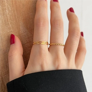 Detailed close-up of gold minimalist twisted rope and multi-layer stackable rings on finger
