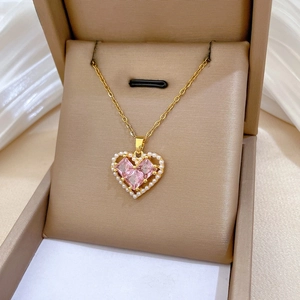 Detailed shot of gold heart necklace with pearls and pink gems in a luxury gift box