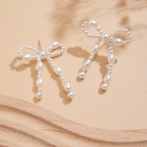 Elegant pearl bow earrings with tassel design on a soft aesthetic background