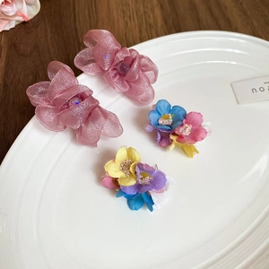 Detailed view of pink chiffon flower hair clips and colorful floral hairpins on a tray