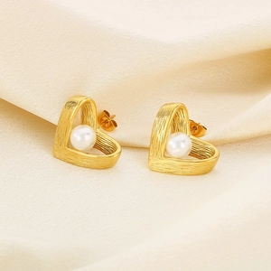 Macro shot of French vintage heart earrings with pearl inlay and brushed gold texture