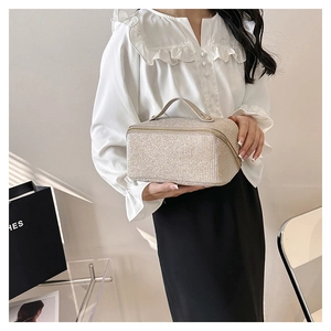 Close-up of champagne woven texture vanity bag with a sleek metal zipper and top handle