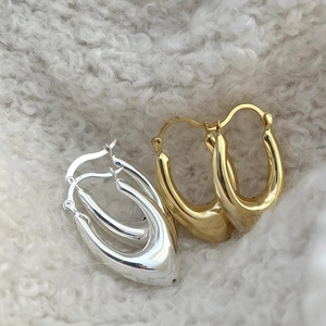 Macro shot of U-shaped 925 silver and gold earrings on white faux fur background